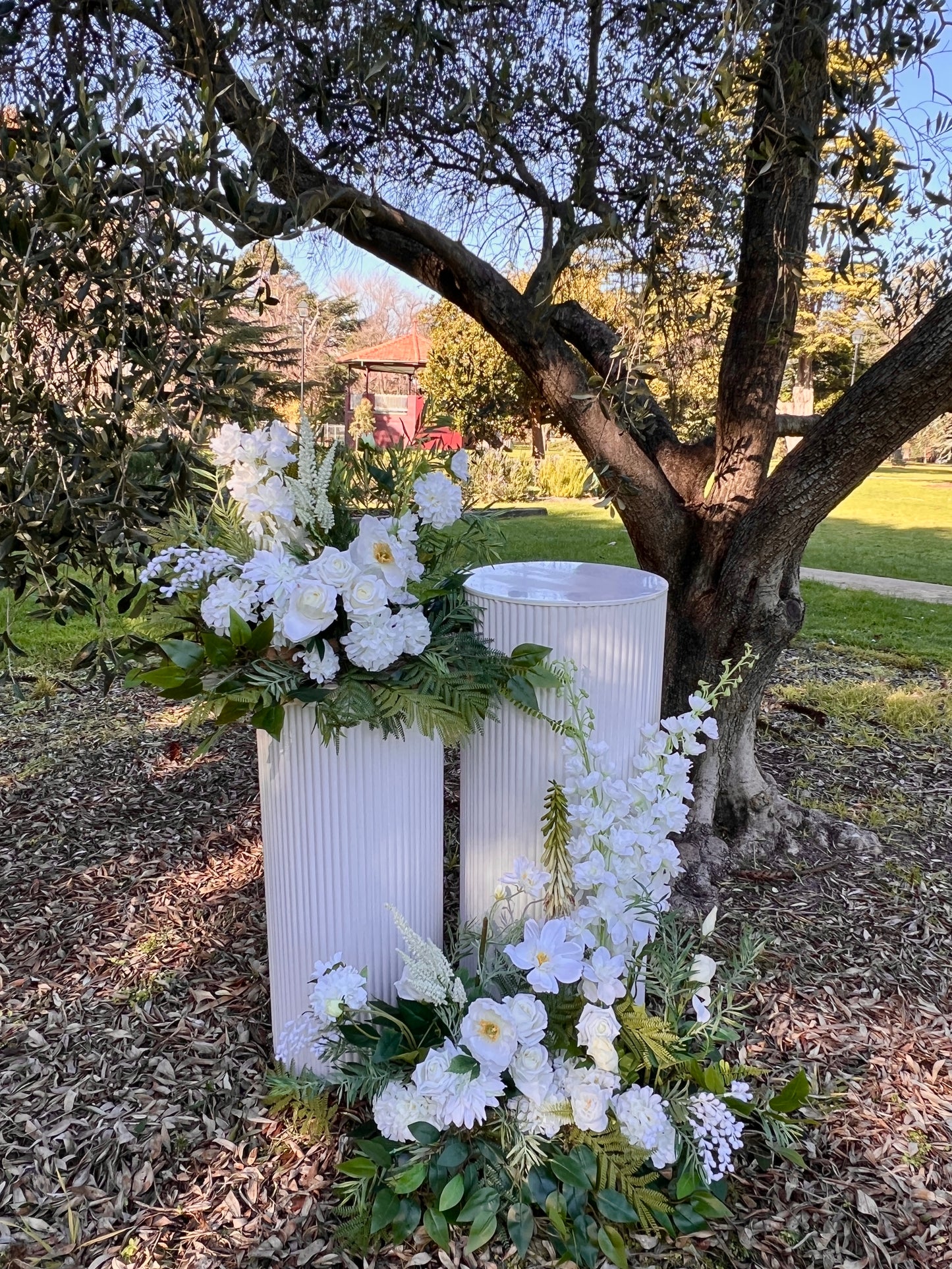 A two plinth setup and florals in white - arrangements made of delphinium, poppy, rose and wattle